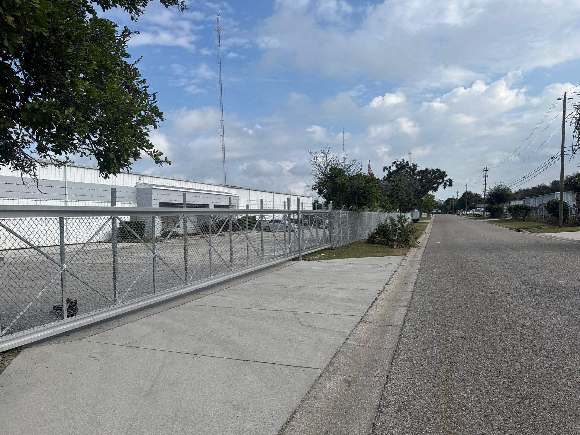 Commercial cantilever driveway gate along a chain-link fence line