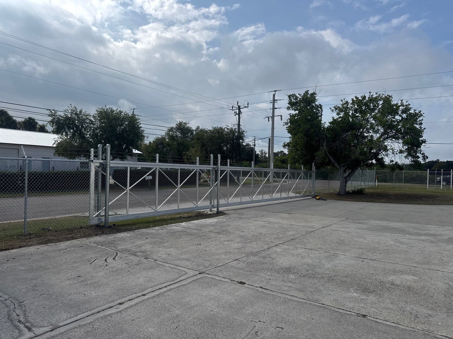 Wide view of a commercial cantilever gate and chain-link fence on a paved yard in Bradenton–Sarasota–Manatee
