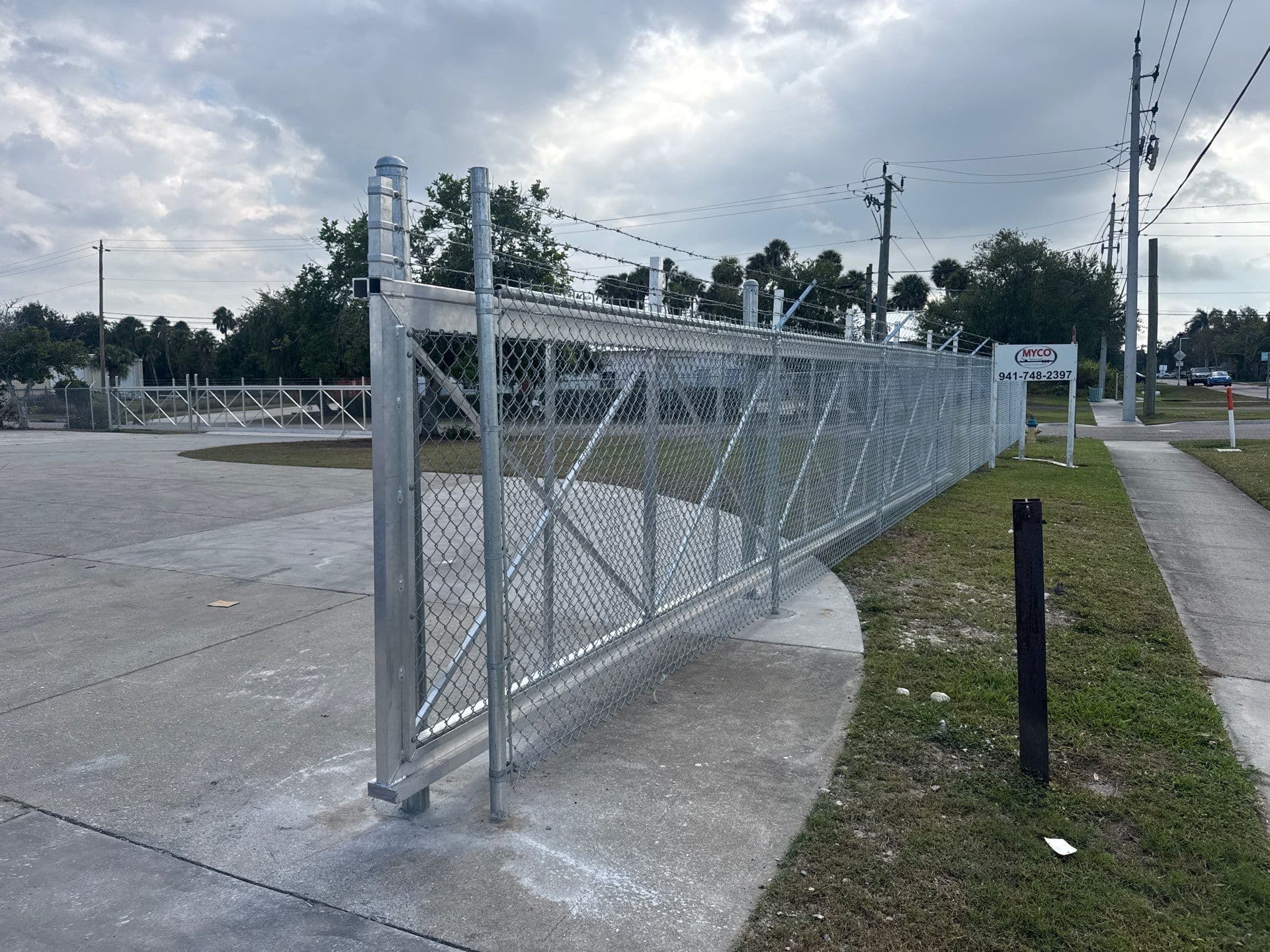 Galvanized commercial cantilever driveway gate with chain-link mesh on a Bradenton–Sarasota–Manatee yard